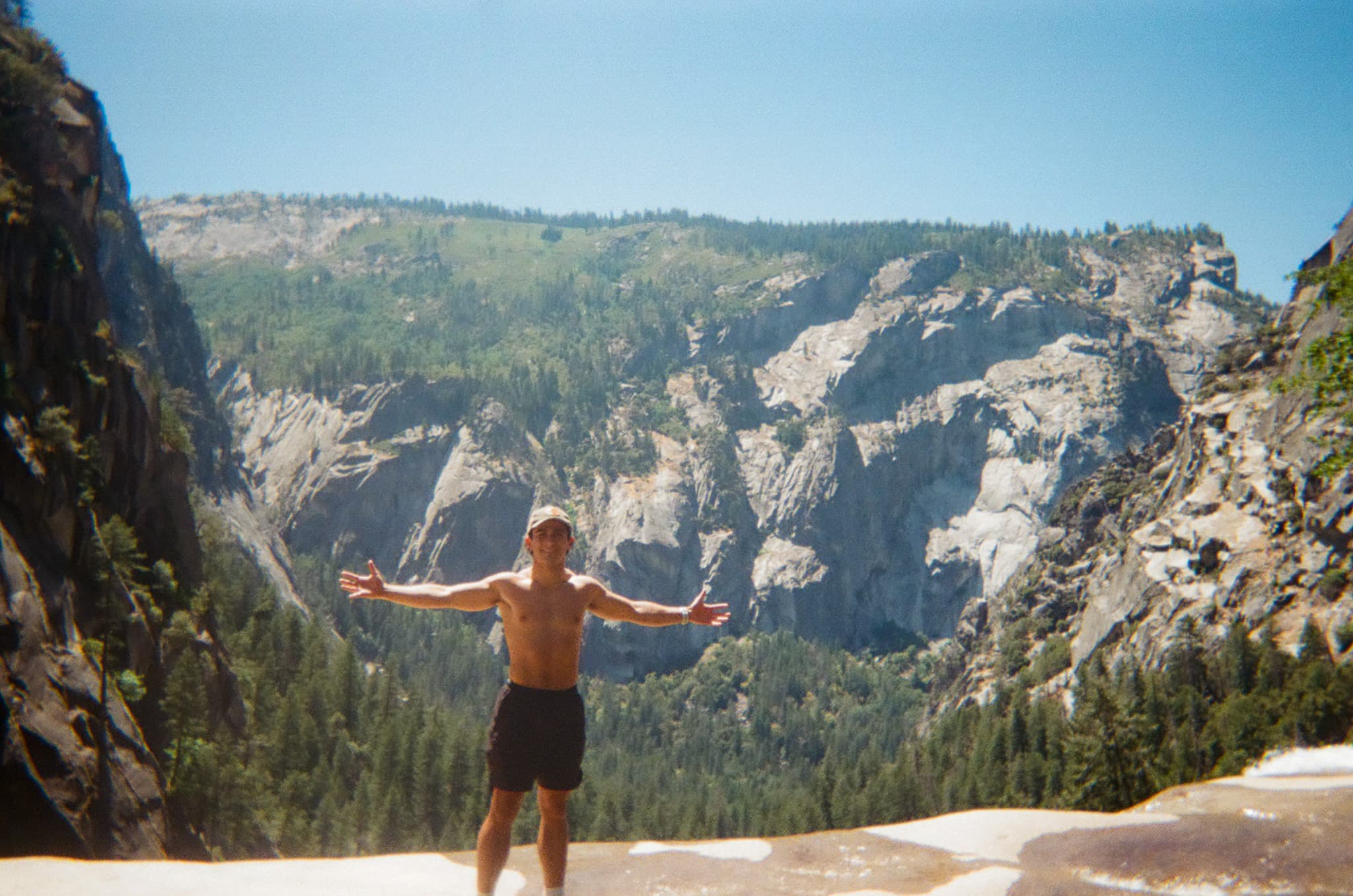 A traveler with arms outstretched above Yosemite Valley